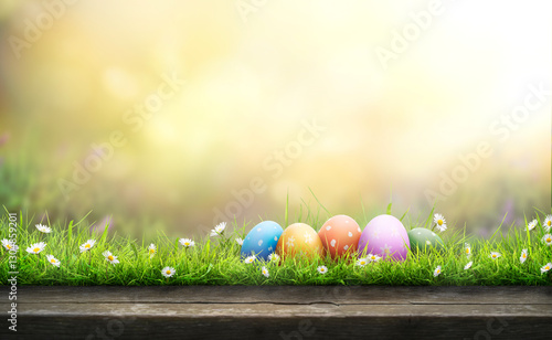 Obraz na płótnie Five painted easter eggs celebrating a Happy Easter on a spring day with a green grass meadow, bright sunlight and a warm colour background with copy space and a wooden bench to display products. w salonie
