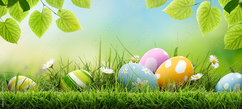 Six painted easter eggs celebrating a Happy Easter on a spring day with a green grass meadow, bright sunlight, tree leaves and a warm colour background with copy space.