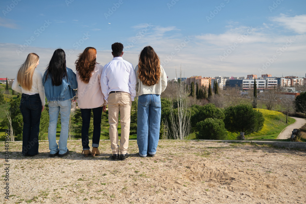 Five students admiring the cityscape from a park on a sunny day Five students admiring the cityscape from a park on a sunny day