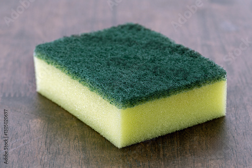 Green rectangular scouring pad with yellow sponge is used for cleaning cups and bowls.
