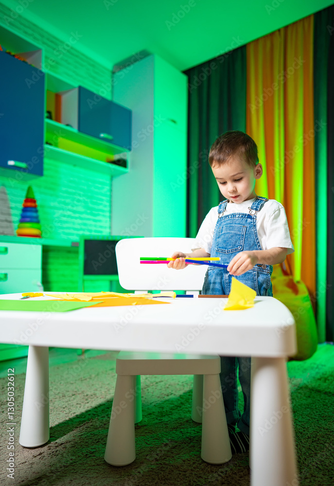 Child enjoying coloring. A young child is focused on coloring at a small table in a brightly colored room, surrounded by artistic supplies. Child enjoying coloring. A young child is focused on coloring at a small table in a brightly colored room, surrounded by artistic supplies.