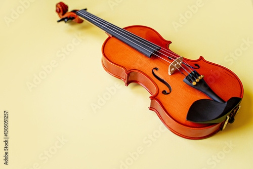 brown wooden graceful sexy lacquered violin, musical instrument lies on a gentle yellow background with space for text photo