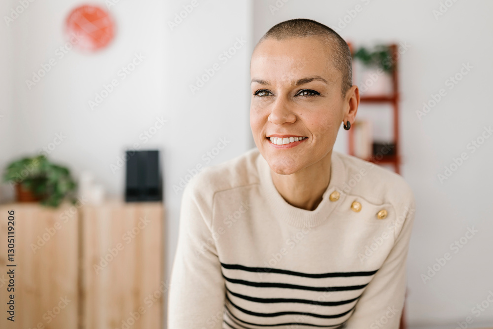 Fototapeta premium Happy mid adult woman sitting at workplace while looking away. Entrepreneur female taking a break from work in the office.