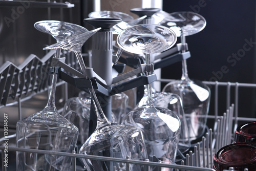 Wine glasses in dishwasher. Clean and tidy. Organizing dishes on holder, loading dirty items.