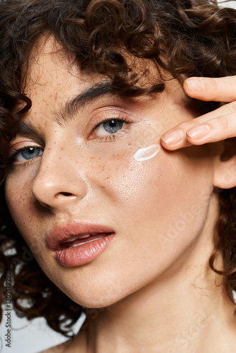 A young woman boosts her natural beauty with cream, radiating confidence.
