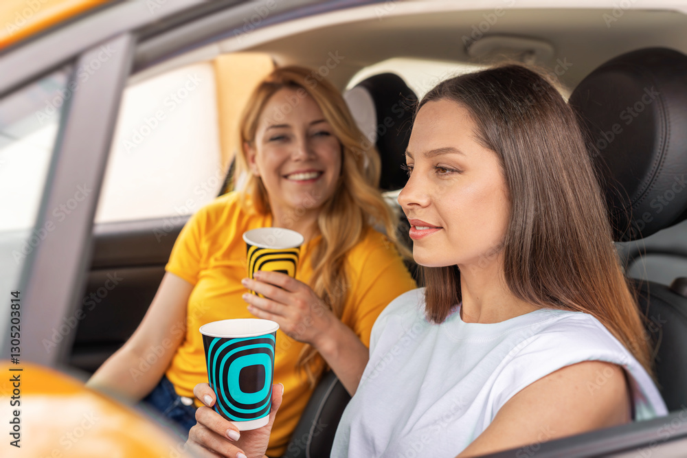 Two women sitting in a car, holding takeaway coffee cups and enjoying a friendly conversation, radiating a warm and relaxed atmosphere.