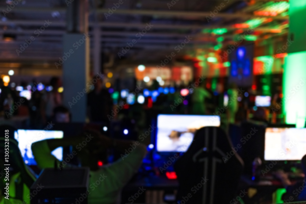 Obraz premium Blurred out of focus indoor space with computer screens and neon lights during esports tournaments and gaming conventions. Gamer gathering concepts.