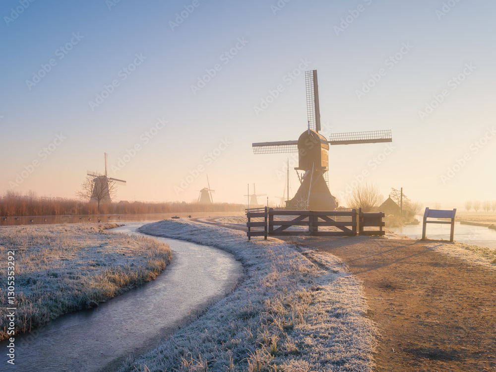 Windmills in the Netherlands during sunrise. Foggy morning and sunshine. Dutch canals. Panoramic natural landscape. Photo for background, wallpaper, postcards.