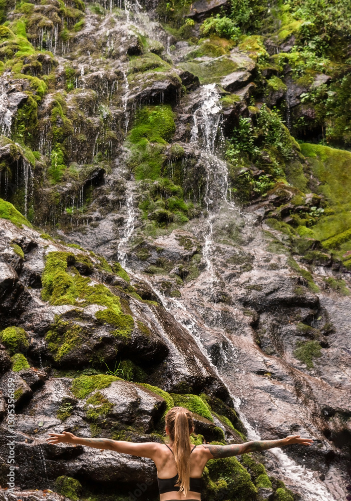 Woman Tourist Standing by Waterfall with Hands Outstretched