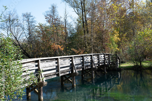 Wooden bridge hit by sun rays in autumn, croissing the river Livenza in Polcenigo (Pordenone)