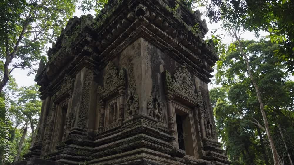 A video captures an ancient stone temple from a low-angle view, surrounded by lush green trees, highlighting intricate carvings and natural beauty. A video captures an ancient stone temple from a low-angle view, surrounded by lush green trees, highlighting intricate carvings and natural beauty.