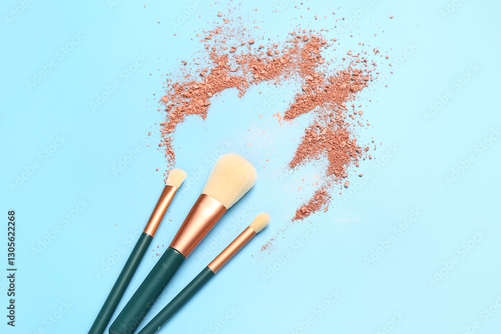 Fototapeta premium Makeup brushes and highlighter on blue background