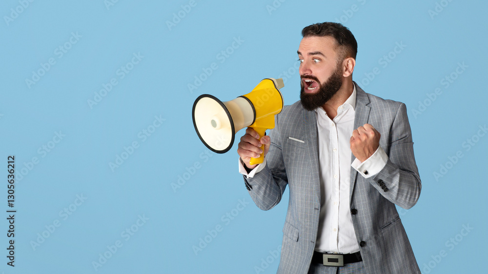 Agitated young businessman in formalwear shouting into megaphone on blue studio background. Emotional millennial office worker making announcement, screaming into loudspeaker Agitated young businessman in formalwear shouting into megaphone on blue studio background. Emotional millennial office worker making announcement, screaming into loudspeaker