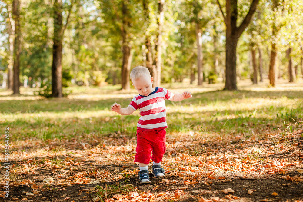 Baby boy in red summer outfit learning to walk outdoors in the park Baby boy in red summer outfit learning to walk outdoors in the park