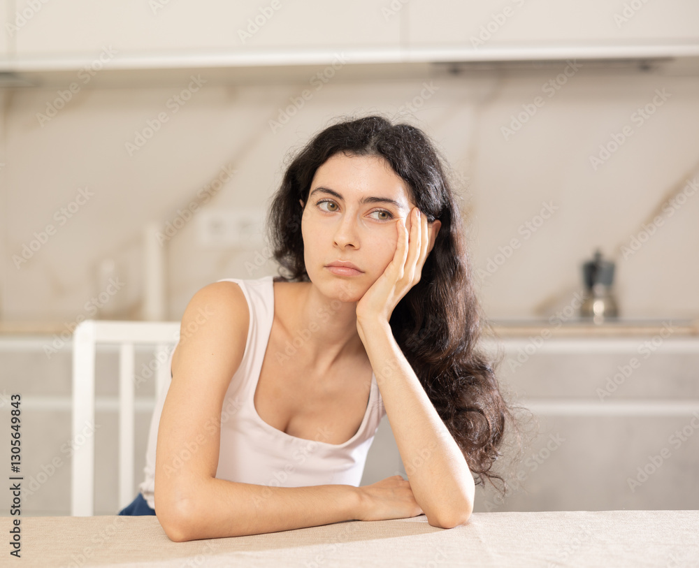Young upset woman in casual clothes posing in kitchen at home Young upset woman in casual clothes posing in kitchen at home
