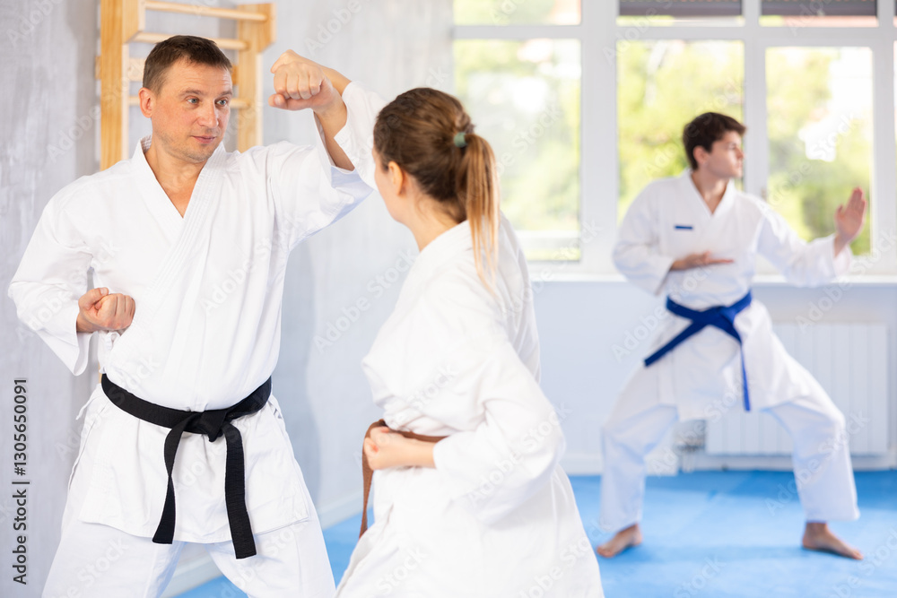 Man and woman train to perform basic defensive installations and attacking actions during combat techniques classes. Young male coach comments and corrects mistakes of students Man and woman train to perform basic defensive installations and attacking actions during combat techniques classes. Young male coach comments and corrects mistakes of students