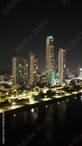 Cinematographic aerial view from a drone at night on a waterfront in Panama City, the night skyline, 4K Vertical video