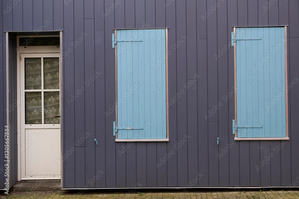A dilapidated structure with a solitary door and boardedup windows, conveying a sense of abandonment A dilapidated structure with a solitary door and boardedup windows, conveying a sense of abandonment