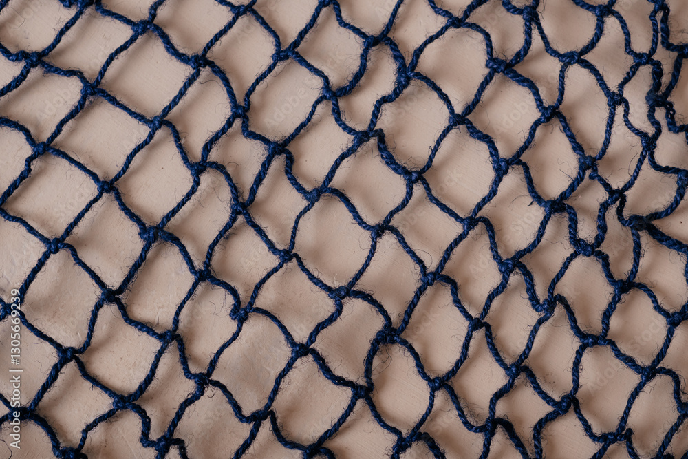 Fototapeta premium A close-up of a fishing net, showcasing its intricate weave and maritime texture, perfect for nautical and coastal themes.