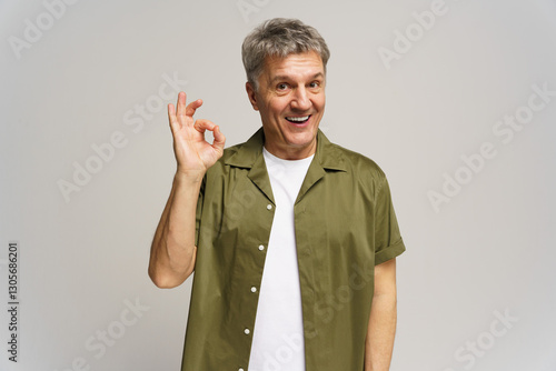 фотографія Middle-aged man expresses positivity with hand gesture while smiling in studio s