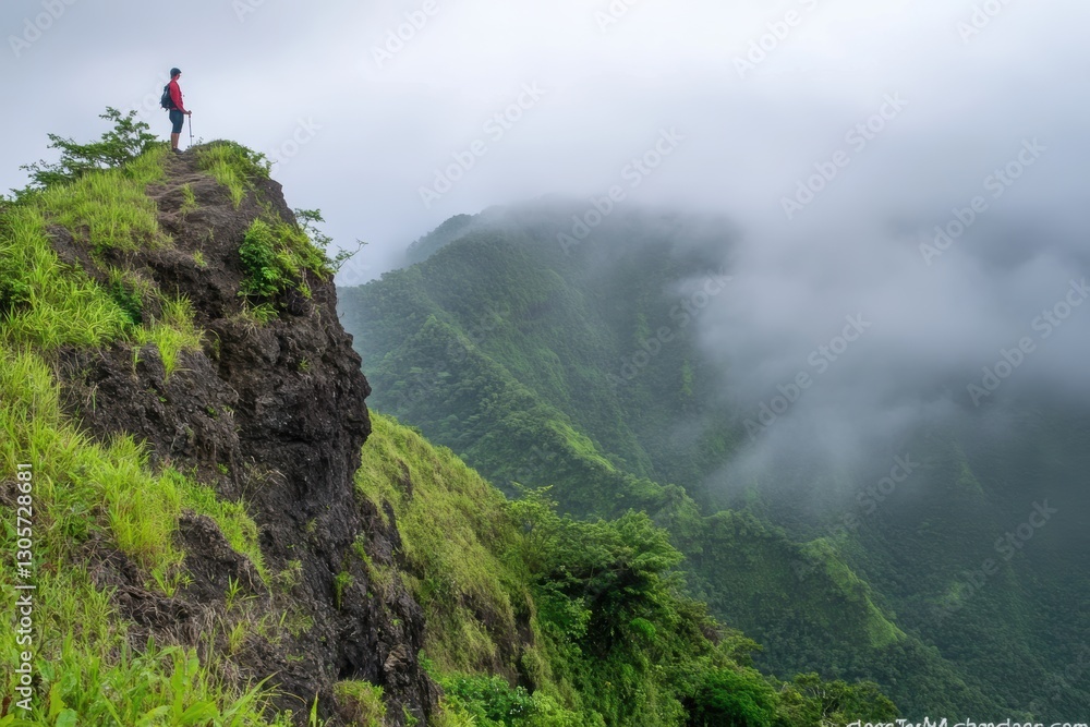 Naklejka premium Giraffe stands on a cliff, gazing at a valley with a mountain backdrop.
