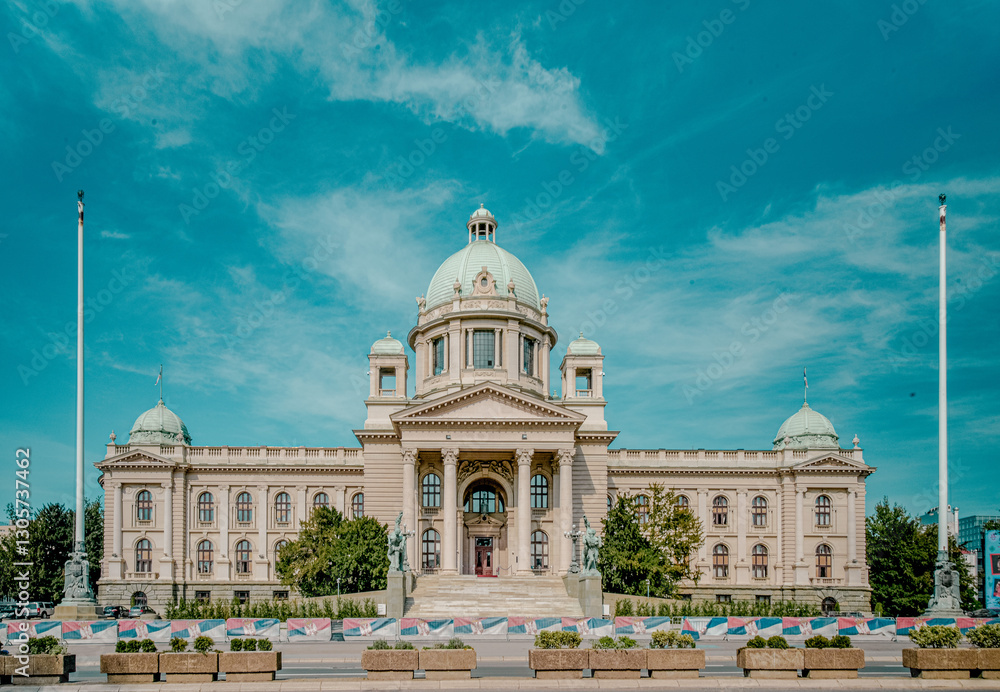 Obraz premium Stunning view of an ornate neoclassical building under a clear blue sky. The architecture features a central dome, symmetrical wings, and detailed sculptures that adorn the facade. 