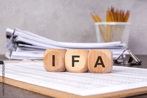 wooden blocks spelling 'IFA' on financial documents, symbolizing investment and financial advisory services