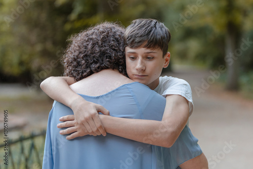 Hug from a worried teenage son to his mother. Tenderness, love, family.