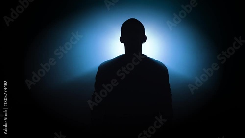 A striking and dramatic silhouette of an individual is beautifully illuminated by a mysterious blue light effect