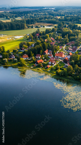 Fototapeta Naklejka Na Ścianę i Meble -  Tranquil lakeside village with traditional houses, surrounded by lush greenery and forests, creating a peaceful and idyllic scene