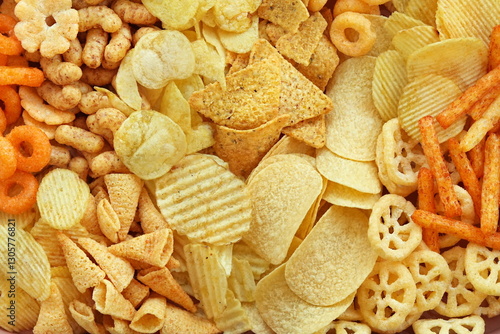Colorful mix of salty snacks for beer varieties: chips and pretzels, onion rings and crackers. Non-healthy junk food background	