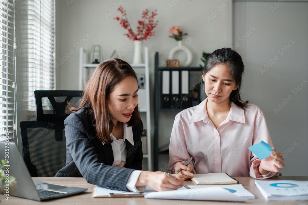 Two women engaged in a business meeting, discussing documents in a modern office environment. Two women engaged in a business meeting, discussing documents in a modern office environment.