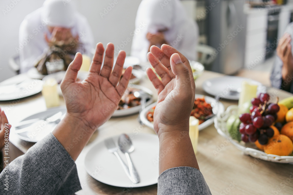 Fototapeta premium Portrait of Raised Hands Praying Before Eating Together With Family On Eid Al Fitr Celebration
