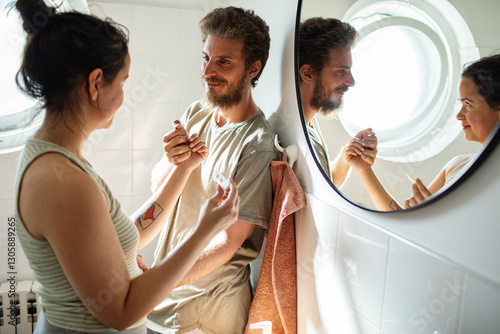 Woman holding positive pregnancy test showing partner in bathroom photo