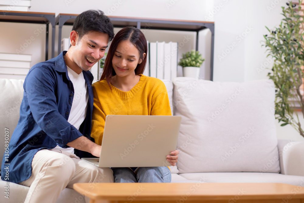 Young asian couple looking on laptop for relax with cozy and contentment sitting on sofa in living room at home, couple leisure watching laptop on couch, relationship and bonding, lifestyle concept. Young asian couple looking on laptop for relax with cozy and contentment sitting on sofa in living room at home, couple leisure watching laptop on couch, relationship and bonding, lifestyle concept.