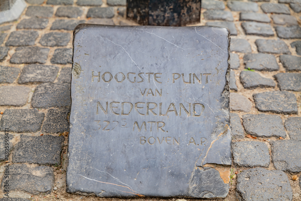 A close-up view of a concrete border marker indicating the highest point in the Netherlands, highlighting the elevation. A close-up view of a concrete border marker indicating the highest point in the Netherlands, highlighting the elevation.
