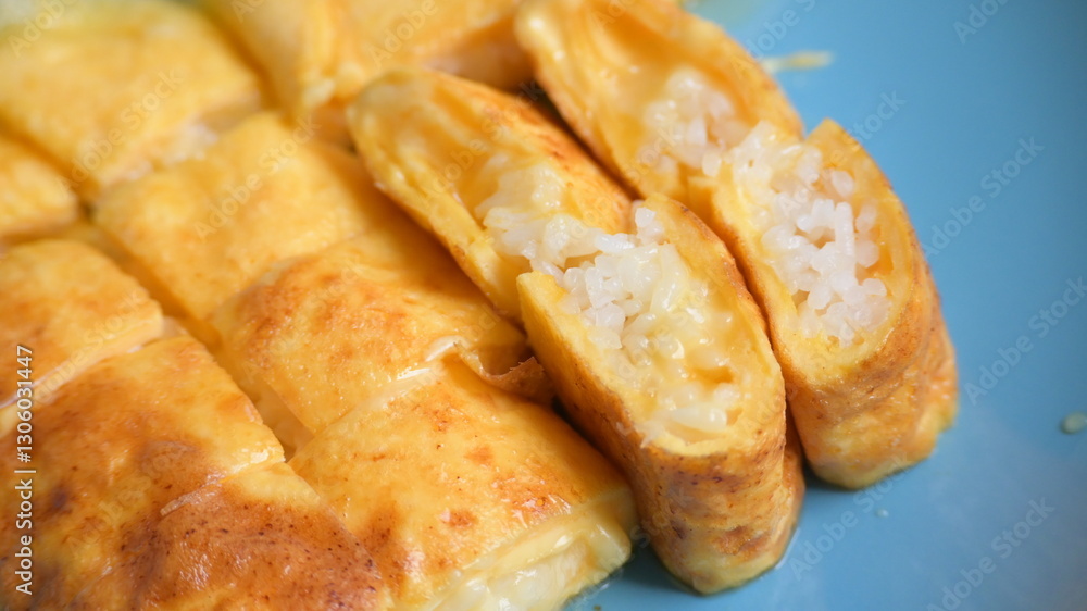 roll omelette stuffed with chesse and rice on blue plate, delicious food in the morning roll omelette stuffed with chesse and rice on blue plate, delicious food in the morning