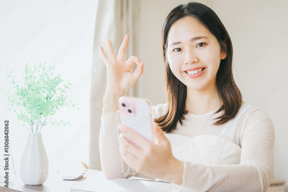 スマホを持ってOKサインする女性
A woman holding a smartphone and making an OK sig スマホを持ってOKサインする女性
A woman holding a smartphone and making an OK sig