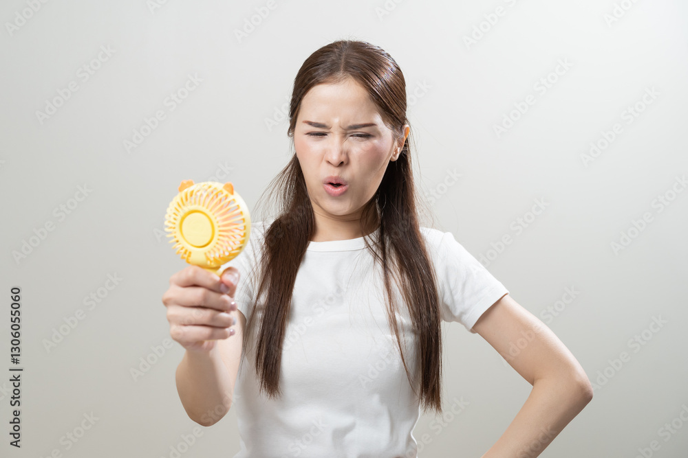 Suffer summer heat wave stroke, hot weather, tired asian young woman sweaty and thirsty, refreshing with hand in blowing, holding electric fan ventilation when temperature high, isolated on background Suffer summer heat wave stroke, hot weather, tired asian young woman sweaty and thirsty, refreshing with hand in blowing, holding electric fan ventilation when temperature high, isolated on background