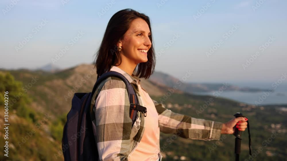 Beautiful, young woman taking a break and enjoying the view while hiking on the mountain Beautiful, young woman taking a break and enjoying the view while hiking on the mountain