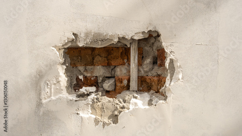 Photography A damaged wall with exposed bricks and cement, revealing the inner structure beneath the cracked and peeled plaster, showing signs of deterioration and construction flaws