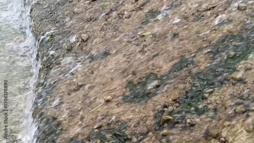 Close Up View Of Water Flowing Over Textured Rocks With Brown And Beige Tones And Gray Undertones. Background Image Of Natural Stream With Water And Close Up View Of Water Flowing Over Textured Rocks With Brown And Beige Tones And Gray Undertones. Background Image Of Natural Stream With Water And