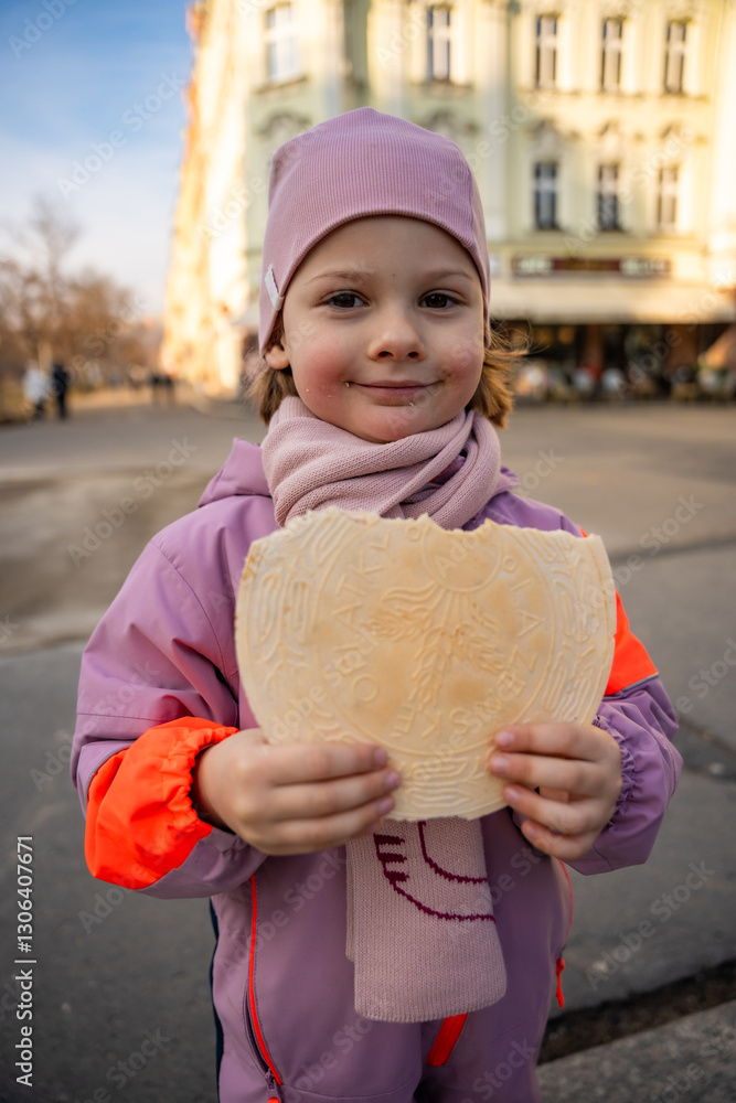 Little girl holding a typical traditional warm waffle or spa waffle in town Karlovy Vary or Carlsbad, Czech Republic Little girl holding a typical traditional warm waffle or spa waffle in town Karlovy Vary or Carlsbad, Czech Republic