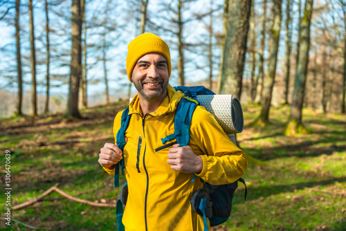 Εκτύπωση καμβά Smiling hiker wearing yellow jacket and backpack hiking in forest