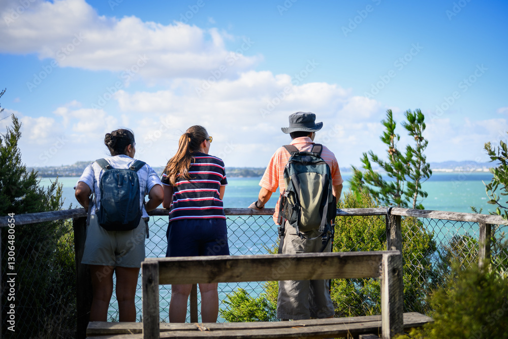 Three people enjoying the view of Waitemata Harbour in summer. Kauri Point Centennial loop track. Auckland.