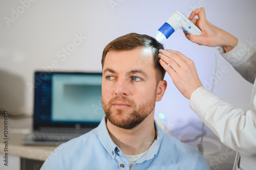 Female doctor looks at a man's scalp with a dermatoscope. Diagnosis of scalp condition by a trichologist. Mole examination, baldness, hair transplantation