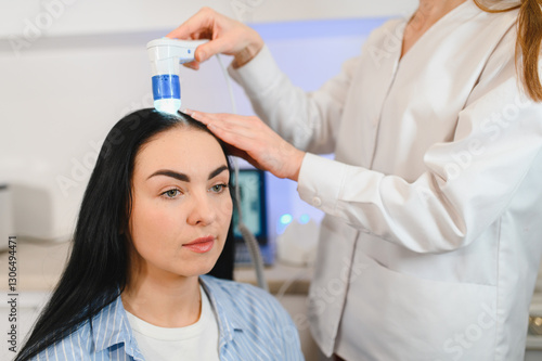 A dermatologist trichologist makes a computer diagnosis of the hair condition of an attractive patient to a young woman. Trichoscopy, trichology photo