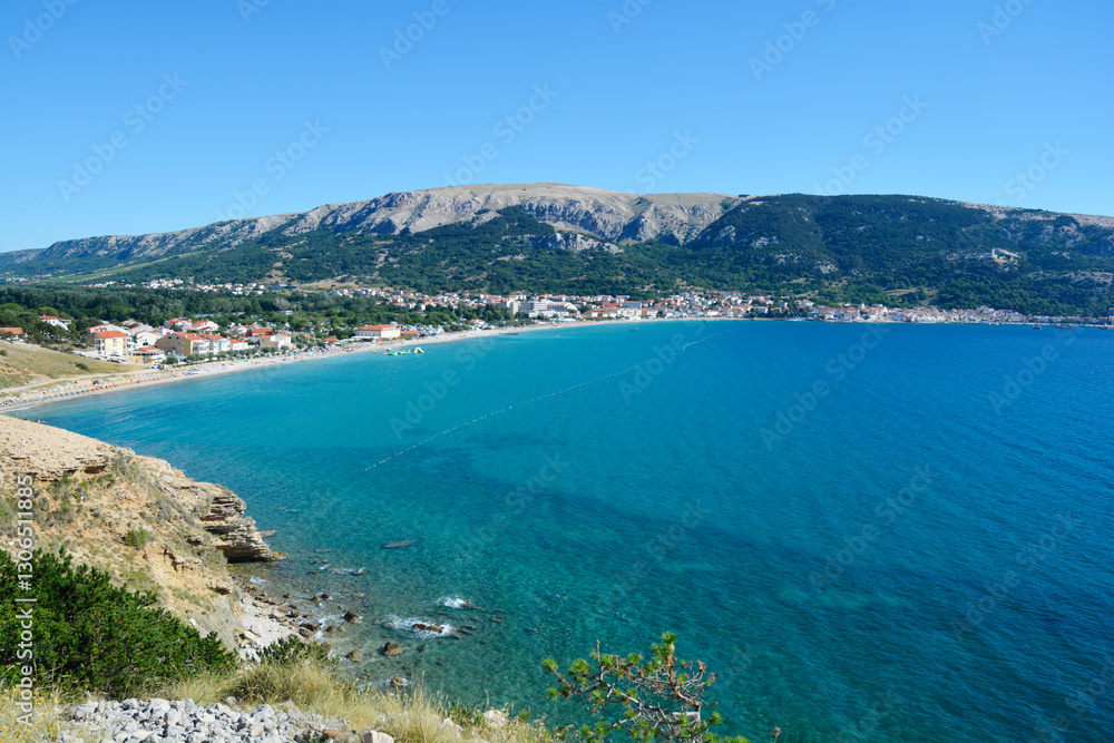 A view of Baska beach (Vela plaza) and the village of the same name, situated by the blue sea, as seen from the rocky western shore of Baska Bay in Croatia A view of Baska beach (Vela plaza) and the village of the same name, situated by the blue sea, as seen from the rocky western shore of Baska Bay in Croatia