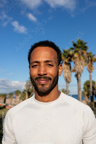 Confident black athlete smiling in tropical location with palm trees