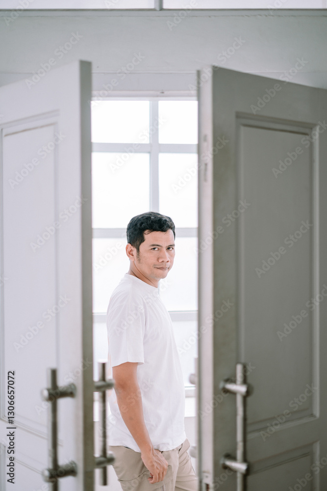 Man Standing Between Open Doors in Bright Interior Setting Man Standing Between Open Doors in Bright Interior Setting